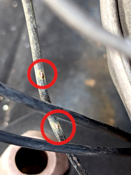 Photograph shows electrical wires rubbing against capillary tubing, resulting in a freon refrigerant leak.